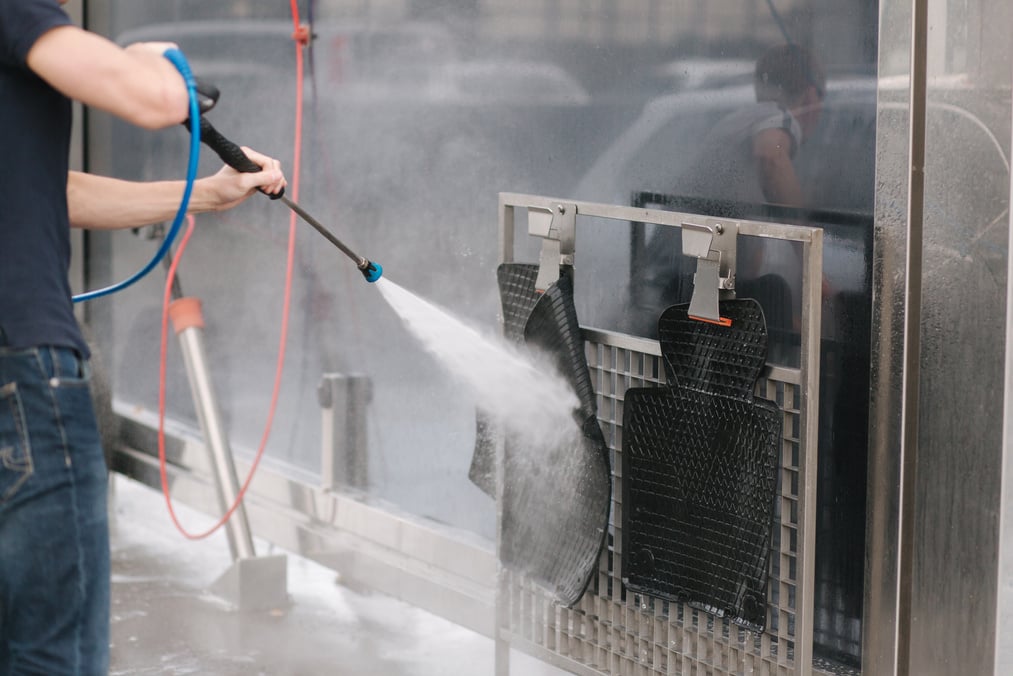 Person Pressure Washing His Car Floor Mats 